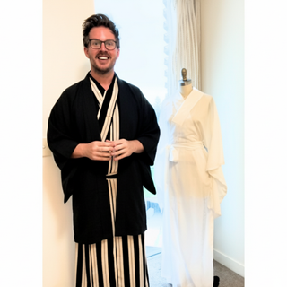 Man in black and white kimono with a dress form displaying a white kimono, showcasing Japanese sewing patterns.