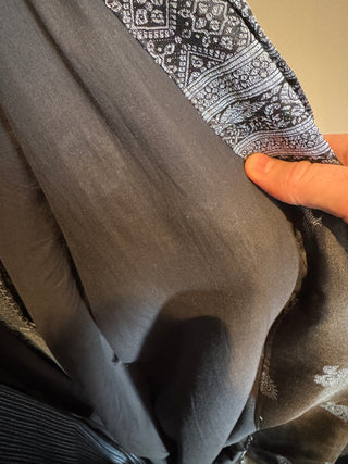 Close-up of a hand holding a black fabric with intricate patterns, showcasing the Haori Yukata & Kimono Sewing Pattern materials.