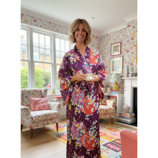 Person wearing a floral kimono, showcasing a Kimono Jacket Sewing Pattern in a cozy living room setting.